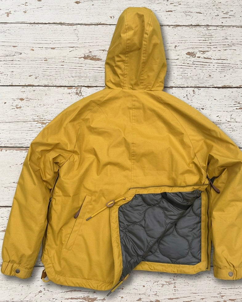 Supermoon Field Parka in Arrowood yellow, product image 6. Showing detailed back view of side zippers open showing contrast onion stitch quilt lining 